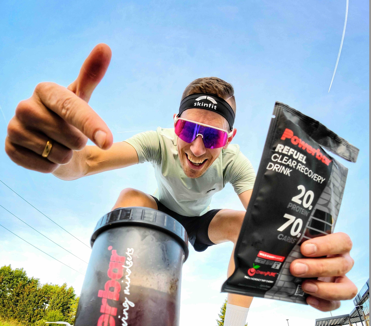 Athlete holds Refuel Clear Recovery Drink in hand and points to shaker.